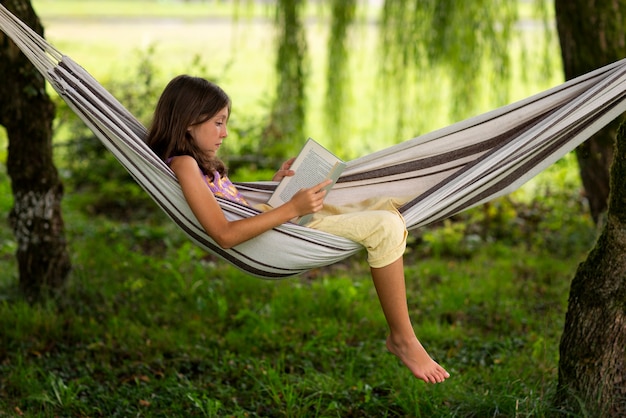 Full shot girl reading in hammock