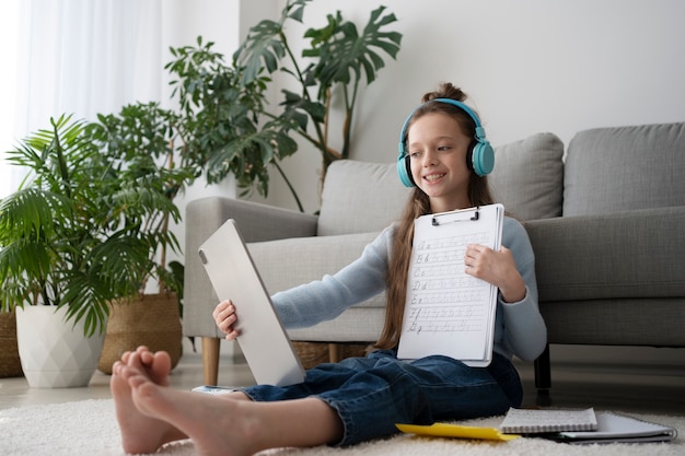 Full shot girl sitting on floor with tablet