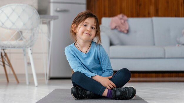 Full shot girl sitting  on yoga mat