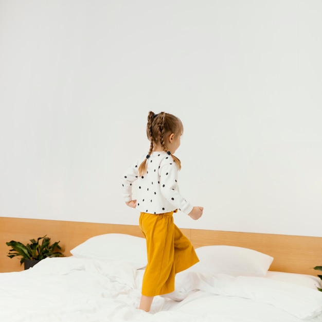 Full shot  girl standing on bed