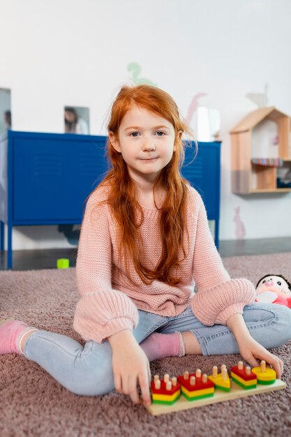 Full shot girl with wooden toy