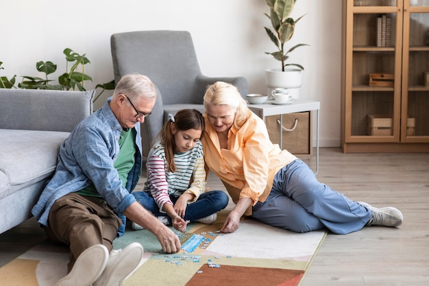 Full shot grandparents and kid doing puzzle