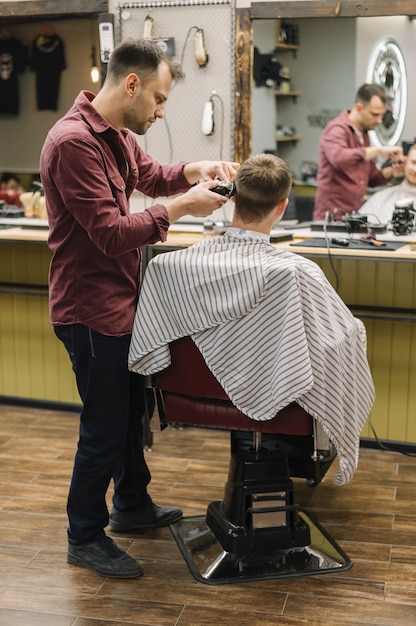 Full shot of hairstylist giving a haircut