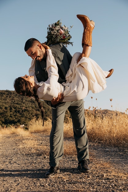 Free photo full shot happy groom holding bride