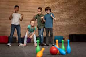 Free photo full shot happy kids playing bowling