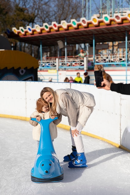 Free photo full shot happy mother with kid at rink