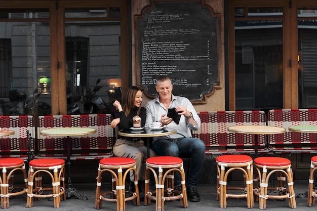 Free Photo full shot happy people sitting at bistro