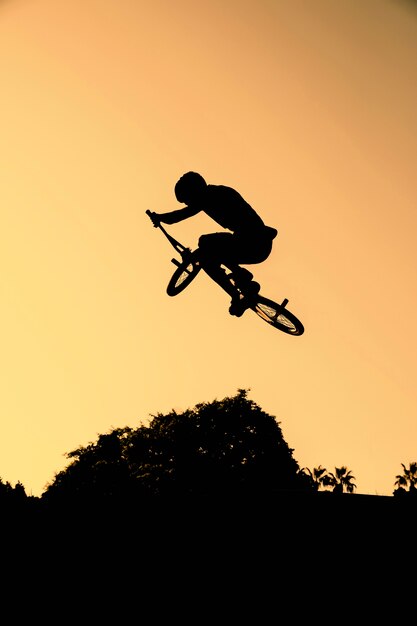 Full shot human silhouette doing tricks on bicycle