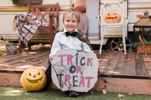 Free Photo full shot kid holding trick or treat sign