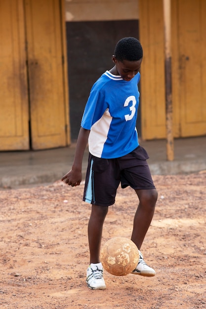 Full shot kid playing with ball outdoors