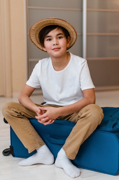 Free photo full shot kid sitting on luggage