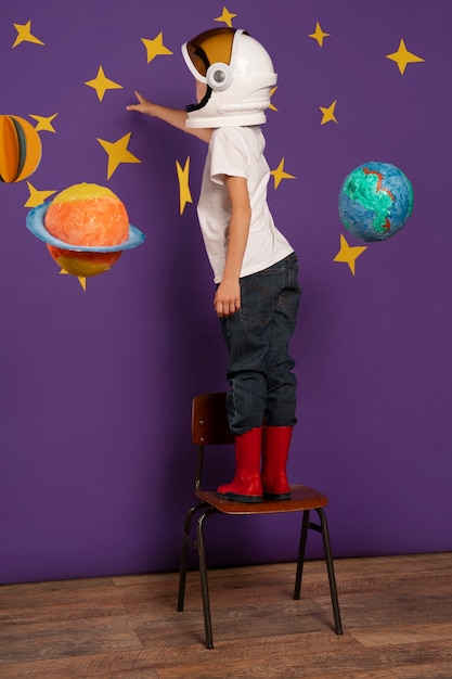 Free photo full shot kid standing on chair indoors