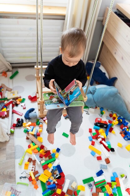 Full shot kid in swing holding book