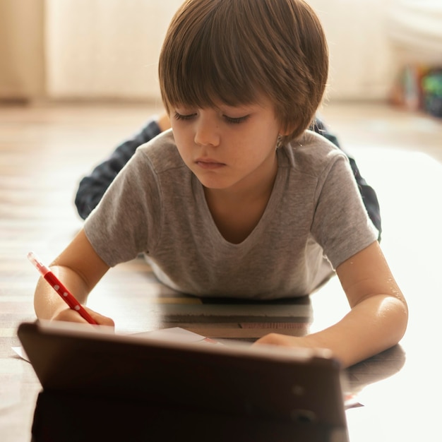 Full shot kid with tablet on floor