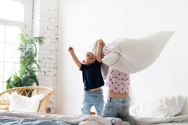 Free Photo full shot kids fighting with pillows