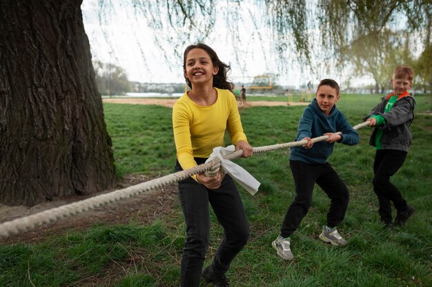 Full shot kids playing tug-of-war in the park