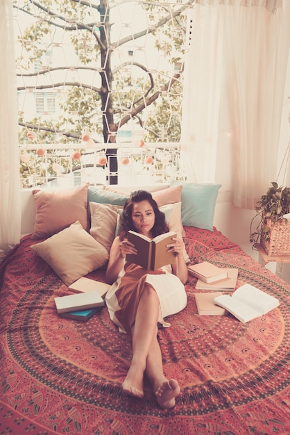 Free photo full shot of lady reading a book lying in her bed