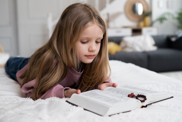 Full shot little girl reading bible