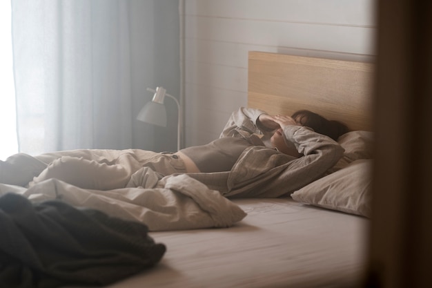 Full shot lonely woman laying in bed