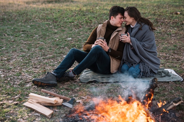 Free photo full shot loving couple near campfire