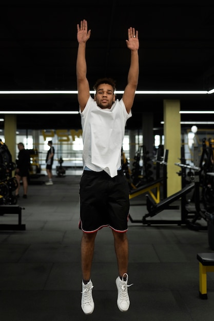 Full shot man doing burpee at gym