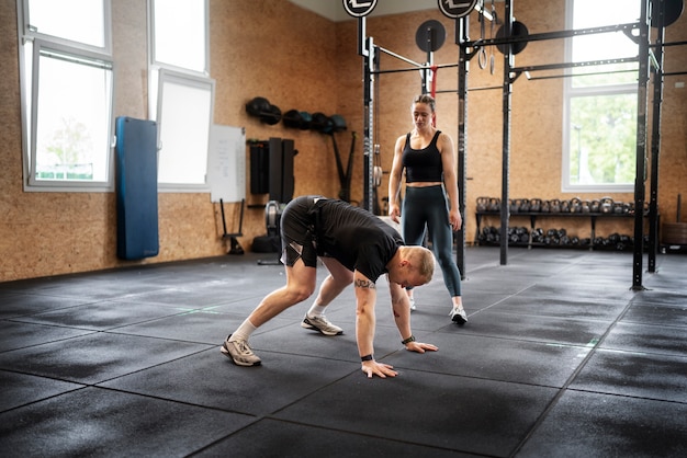 Free photo full shot man doing burpees at gym