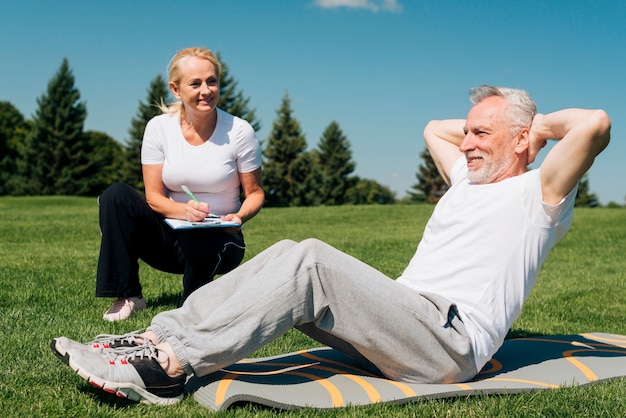 Full shot man doing crunches in nature