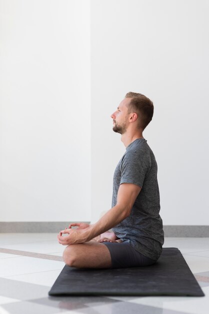 Full shot man doing sukhasana pose indoor