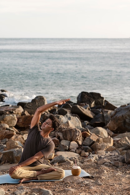 Free photo full shot man doing yoga on mat