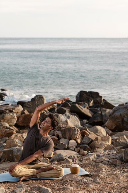 Full shot man doing yoga on mat