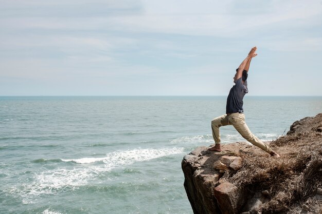 Full shot man doing yoga at seaside