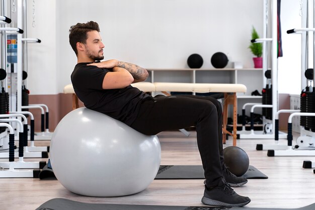 Full shot man exercising with ball