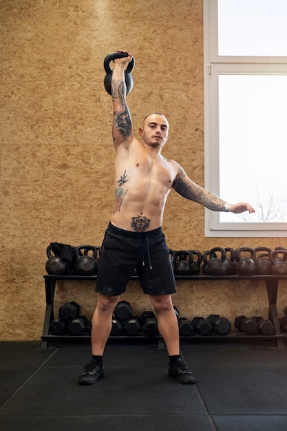 Free photo full shot man exercising with kettlebell indoors