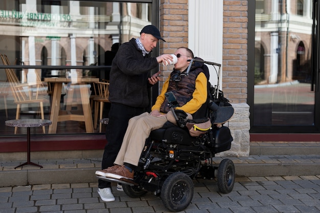 Free photo full shot man helping disabled friend drink