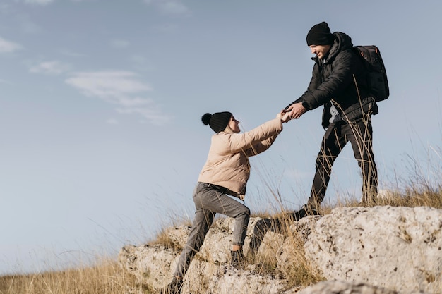 Full shot man helping woman climb