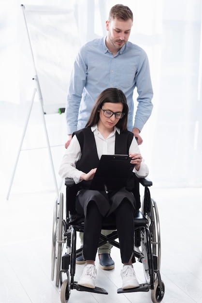 Full shot man helping woman in wheelchair