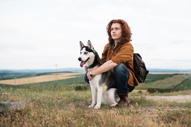 Full shot man holding dog in nature