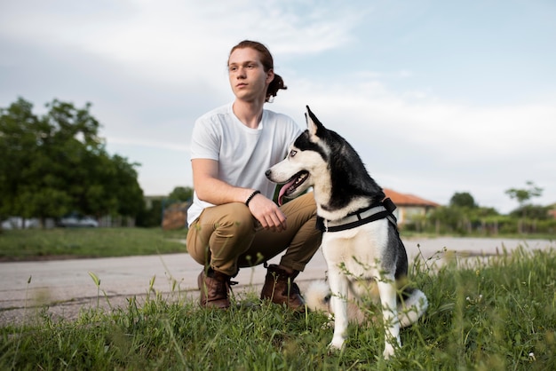 Free Photo full shot man holding husky outdoors