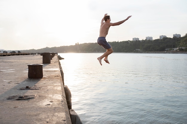 Free photo full shot man jumping in water