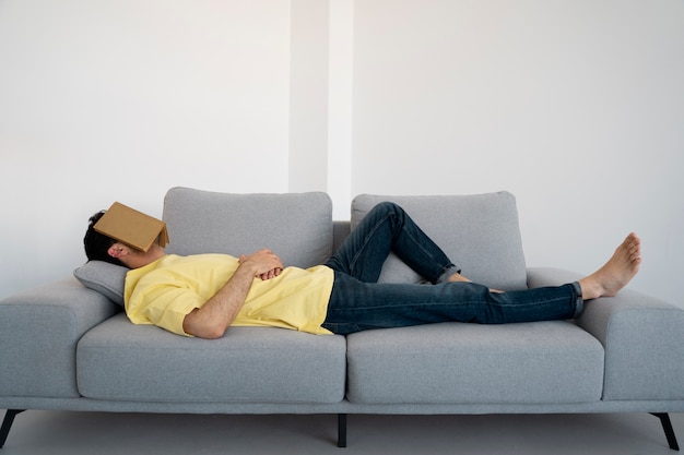 Free photo full shot man laying on couch with book