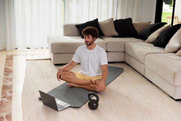 Full shot man meditating on mat