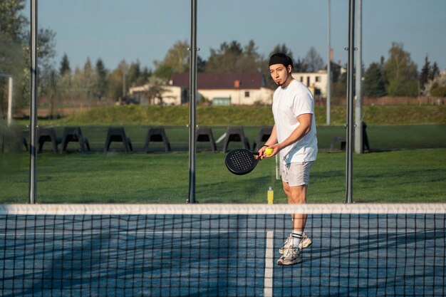 Full shot man playing paddle tennis outdoors