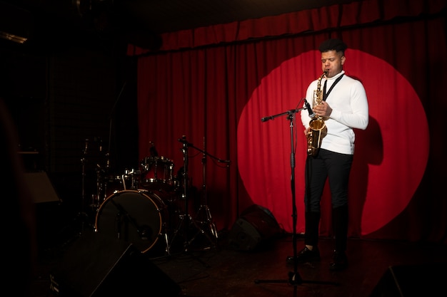 Free Photo full shot man playing the saxophone