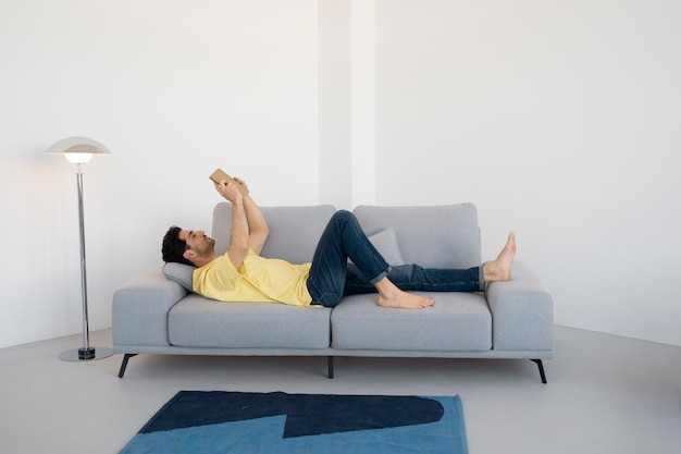 Full shot man reading on couch