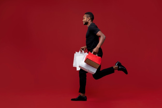 Full shot man running with shopping bags