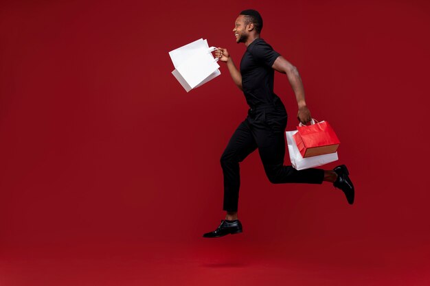 Full shot man running with shopping bags