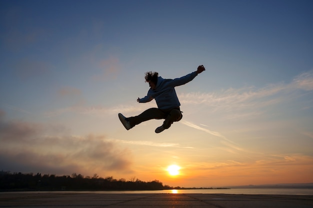 Free photo full shot man silhouette jumping at sunset