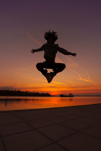 Free photo full shot man silhouette jumping at sunset