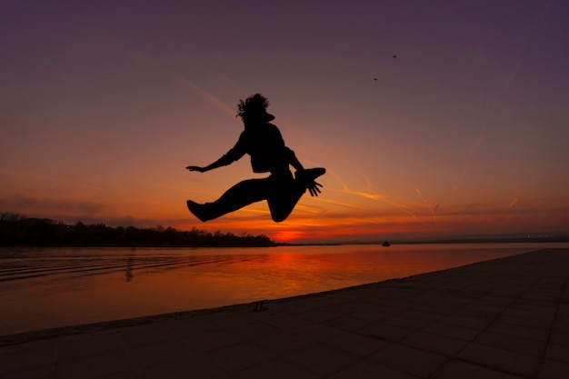 Full shot man silhouette jumping at sunset