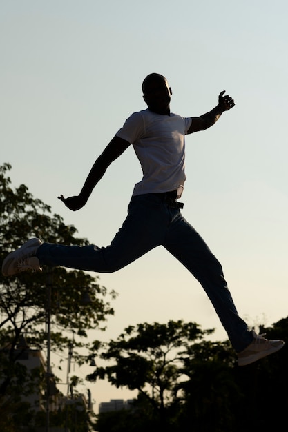 Free photo full shot man silhouette jumping at sunset